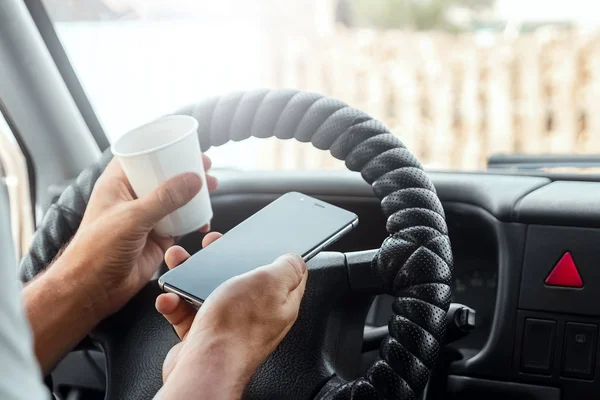 Muž za volantem, držící v ruce smartphone, porušuje dopravní předpisy. Koncept nehody, narušení provozu, telefon za volantem — Stock fotografie