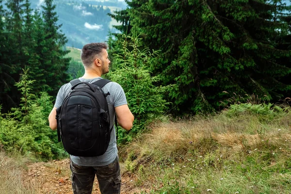 Touriste masculin avec un sac à dos debout au sommet d'une montagne admirant le paysage. Le concept de vacances actives, voyage, vacances à la montagne, style de vie — Photo