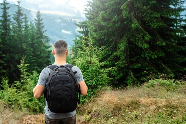 Чоловік турист з рюкзаком, що стоїть на вершині гори, милуючись пейзажем. Концепція активних свят, подорожей, відпочинку в горах, спосіб життя — стокове фото
