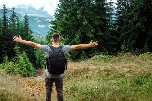 Ein männlicher Tourist mit Rucksack steht auf einem Berg und bewundert die Landschaft. das Konzept von Aktivurlaub, Reisen, Urlaub in den Bergen, Lebensstil — Stockfoto