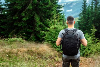 Bir sırt çantası ile erkek turist manzara hayran bir dağın tepesinde duruyor. Aktif tatil kavramı, seyahat, dağlarda tatil, yaşam tarzı
