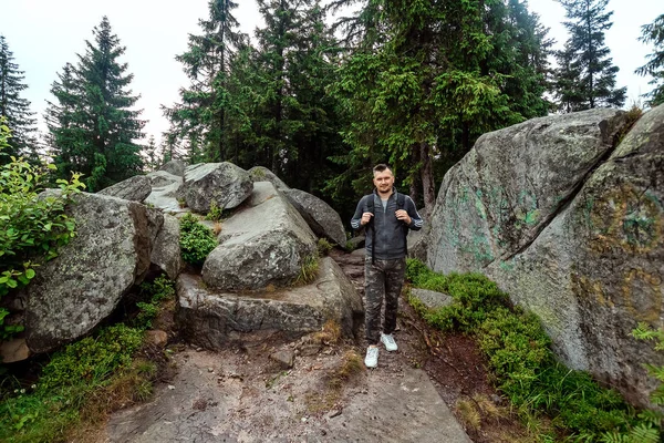 Un hombre es un turista con una mochila, camina por las montañas, hace senderismo. El concepto de vacaciones activas, viajes, vacaciones en la montaña, estilo de vida —  Fotos de Stock