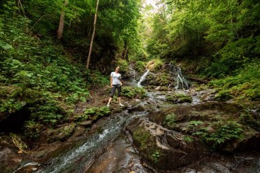 Küçük bir şelalede güzel kız, Karpat dağ deresi. Seyahat konsepti, boş zaman aktivitesi, tatil