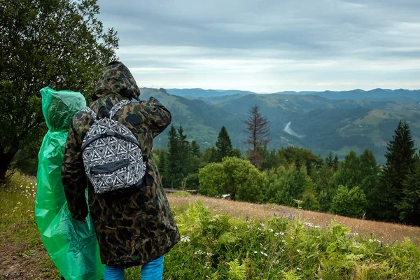 Pareja, turistas en un impermeable sobre un fondo de hermosas montañas Cárpatos. Levántate en las montañas. Concepto de viaje, actividad de ocio, vacaciones —  Fotos de Stock