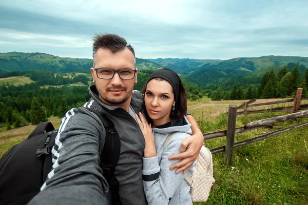 Hermosa pareja, turistas, hacer selfie, foto sobre el fondo de las hermosas montañas de los Cárpatos. Concepto de viaje, actividad de ocio, vacaciones —  Fotos de Stock