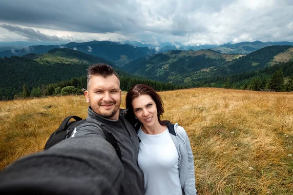 Beau couple, touristes, faire du selfie, photo sur le fond des belles montagnes des Carpates. Concept de voyage, activité de loisirs, vacances — Photo