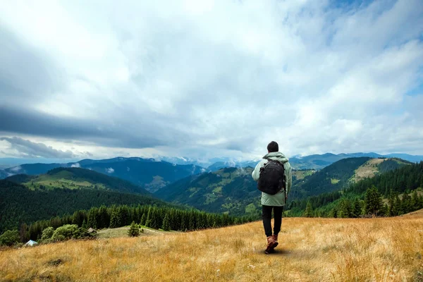 Sfondo creativo, Un turista di sesso maschile cammina attraverso una zona montuosa con uno zaino. Il concetto di turismo attivo, ricreazione, i Carpazi. Copia spazio — Foto Stock