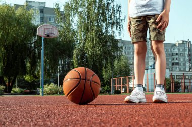 Basketbol sahasında basketbol topu olan bir çocuğun portresi. Bir spor yaşam tarzı kavramı, eğitim, spor, eğlence, tatil.
