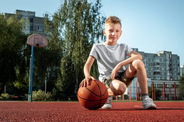 Basketbol sahasında basketbol topu olan bir çocuğun portresi. Bir spor yaşam tarzı kavramı, eğitim, spor, eğlence, tatil.