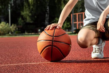 Çocuk elinde bir basketbol yakın çekim tutar, bir basketbol sahası arka plan karşı. Bir spor yaşam tarzı kavramı, eğitim, spor, eğlence, tatil.