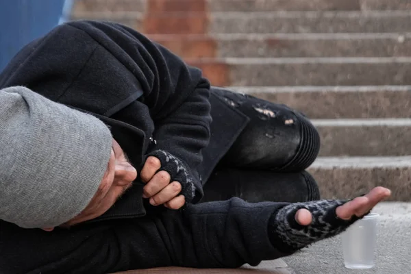 ホームレスの男が、ヘルプサインを持って路上でアルムを求める。ホームレス、社会問題、薬物中毒者、貧困、絶望の概念. — ストック写真