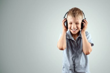 Beyaz gülümseyen çocuk, açık arka planda büyük kulaklıklarla müzik dinler. Müzisyen, çocuğun geleceği, müzik sever.