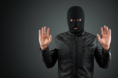Soyguncu, bir balaclava bir haydut siyah bir arka plan üzerinde ellerini kaldırdı, teslim oldu. Soygun, hacker, suç, hırsızlık, tutuklama. Kopyalama alanı.