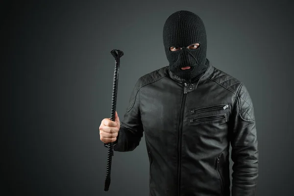 Rabló, Bandit egy Balaclava egy feszítő bár a kezében egy fekete háttér. Rablás, hacker, bűncselekmény, lopás. Lemezterület másolása. — Stock Fotó