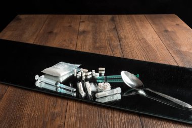 Bir sürü farklı ilaç, şırınga, masada haplar. Sosyal sorun, uyuşturucu bağımlılığı, ölüm, bağımlılık. Kopyalama alanı.