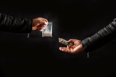 Paralı bir uyuşturucu bağımlısının eli, siyah bir arka plandaki bir uyuşturucu satıcısından bir doz kokain ya da başka bir uyuşturucu almak. Sosyal sorun, uyuşturucu bağımlılığı. Kopyalama alanı.