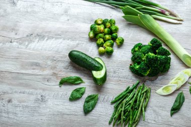 Hafif bir masada taze yeşil yemek. Avokado salatalık lahana elma fasulye kivi soğan brokoli. Sağlıklı gıda kavramı, detoks vejetaryenlik. Kopya alanı düz yatıyordu.