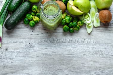 Hafif bir masada taze yeşil yemek. Avokado salatalık lahana elma fasulye kivi soğan brokoli. Sağlıklı gıda kavramı, detoks vejetaryenlik. Kopya alanı düz yatıyordu.