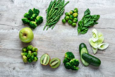 Hafif bir masada taze yeşil yemek. Avokado salatalık lahana elma fasulye kivi soğan brokoli. Sağlıklı gıda kavramı, detoks vejetaryenlik. Kopya alanı düz yatıyordu.