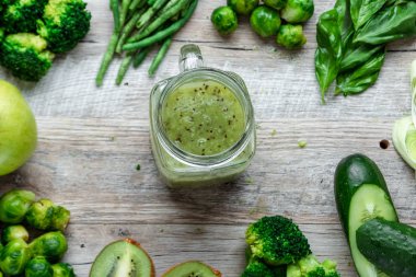 Hafif bir masada taze yeşil yemek. Avokado salatalık lahana elma fasulye kivi soğan brokoli. Sağlıklı gıda kavramı, detoks vejetaryenlik. Kopya alanı düz yatıyordu.