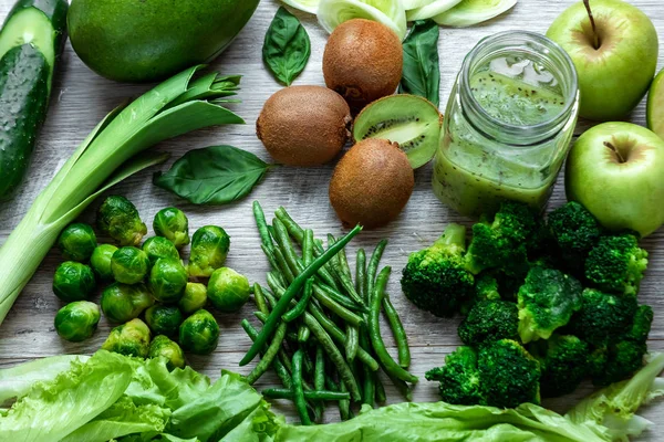 Fresh green food on a light table. Avocados cucumbers cabbage apples beans kiwi onions broccoli. The concept of healthy food, detox vegetarianism. Copy space flat lay.