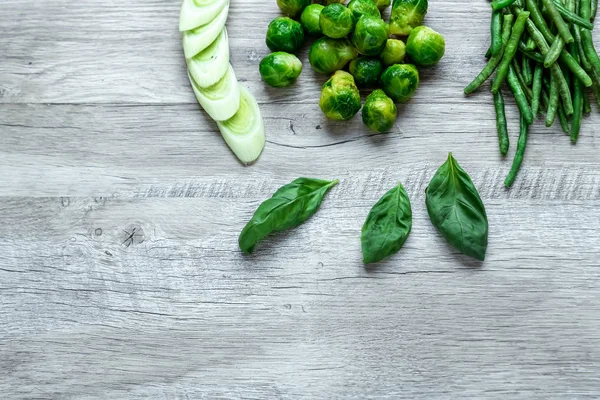 Hafif bir masada taze yeşil yemek. Avokado salatalık lahana elma fasulye kivi soğan brokoli. Sağlıklı gıda kavramı, detoks vejetaryenlik. Kopya alanı düz yatıyordu.
