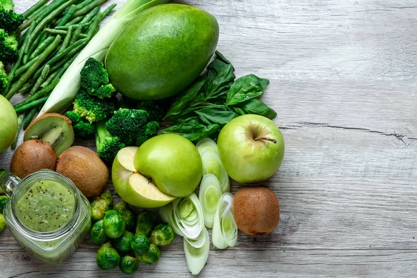 Hafif bir masada taze yeşil yemek. Avokado salatalık lahana elma fasulye kivi soğan brokoli. Sağlıklı gıda kavramı, detoks vejetaryenlik. Kopya alanı düz yatıyordu.