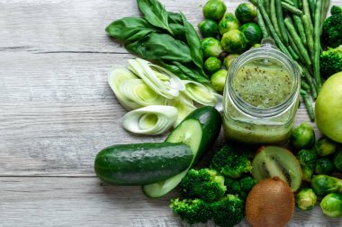 Hafif bir masada taze yeşil yemek. Avokado salatalık lahana elma fasulye kivi soğan brokoli. Sağlıklı gıda kavramı, detoks vejetaryenlik. Kopya alanı düz yatıyordu.