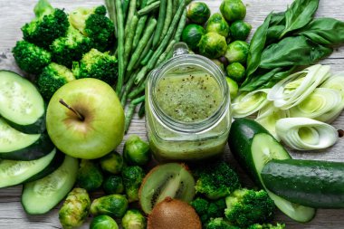 Hafif bir masada taze yeşil yemek. Avokado salatalık lahana elma fasulye kivi soğan brokoli. Sağlıklı gıda kavramı, detoks vejetaryenlik. Kopya alanı düz yatıyordu.