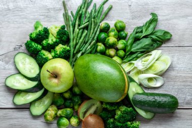 Hafif bir masada taze yeşil yemek. Avokado salatalık lahana elma fasulye kivi soğan brokoli. Sağlıklı gıda kavramı, detoks vejetaryenlik. Kopya alanı düz yatıyordu.