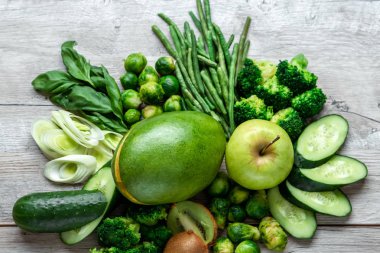 Hafif bir masada taze yeşil yemek. Avokado salatalık lahana elma fasulye kivi soğan brokoli. Sağlıklı gıda kavramı, detoks vejetaryenlik. Kopya alanı düz yatıyordu.
