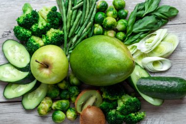 Hafif bir masada taze yeşil yemek. Avokado salatalık lahana elma fasulye kivi soğan brokoli. Sağlıklı gıda kavramı, detoks vejetaryenlik. Kopya alanı düz yatıyordu.