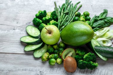 Hafif bir masada taze yeşil yemek. Avokado salatalık lahana elma fasulye kivi soğan brokoli. Sağlıklı gıda kavramı, detoks vejetaryenlik. Kopya alanı düz yatıyordu.