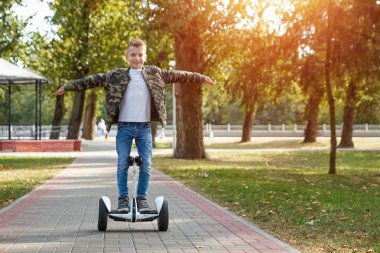 Parkta hoverboard'a binen bir çocuk, kendini dengeleyen bir scooter. Aktif yaşam tarzı teknolojisi gelecek
