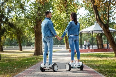 Parkta hoverboard'a binen genç bir çift, kendini dengeleyen bir scooter. Aktif yaşam tarzı teknolojisi gelecek
