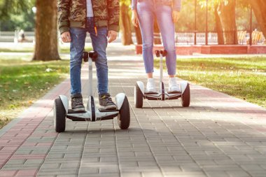 Parkta hoverboard'a binen genç bir çift, kendini dengeleyen bir scooter. Aktif yaşam tarzı teknolojisi gelecek