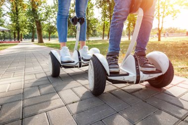 Parkta hoverboard'a binen genç bir çift, kendini dengeleyen bir scooter. Aktif yaşam tarzı teknolojisi gelecek
