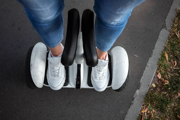 Benen van een meisje in witte sneakers op een witte Hoverboard, zelfbalancerende scooter in een park close-up. Actieve lifestyle technologie toekomstige Kopieer ruimte — Stockfoto
