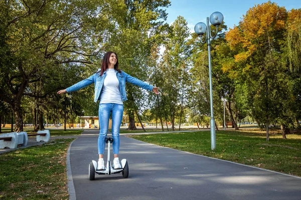 Hermosa chica en un hoverboard blanco en el parque, auto-equilibrio scooter. Estilo de vida activo tecnología futuro espacio de copia — Foto de Stock