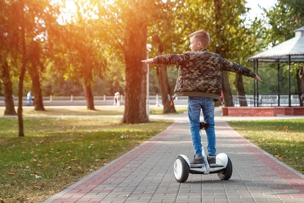 Un ragazzo che cavalca un hoverboard nel parco, uno scooter auto-bilanciante. Stile di vita attivo tecnologia futuro — Foto Stock