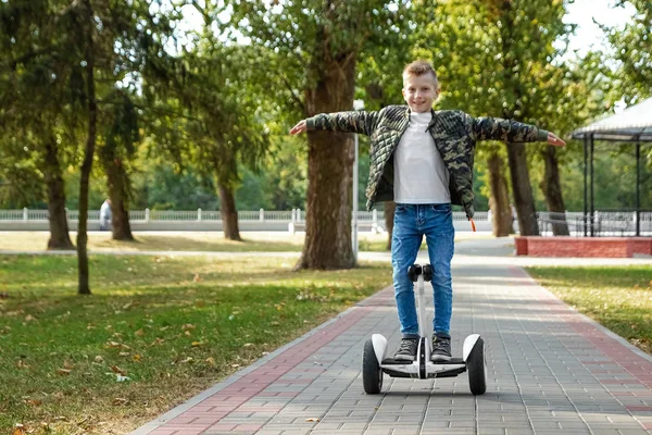 Un chico montando un hoverboard en el parque, un scooter auto-equilibrado. Tecnología de estilo de vida activo futuro — Foto de Stock