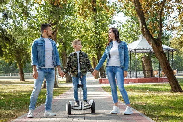 Modern family, dad mom son rides a hoverboard in the park, self-balancing scooter. Active lifestyle technology future