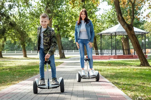 Mamá e hijo montan en un hoverboard en el parque, un scooter auto-equilibrado. Tiempo de estilo de vida activo con tecnología de bebé futuro —  Fotos de Stock