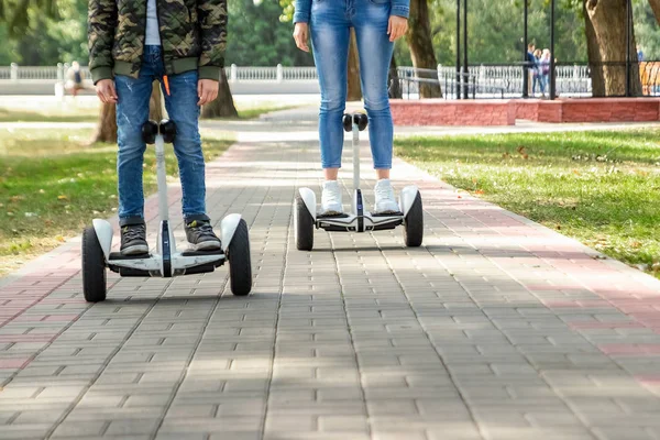 Een jong stel rijdt op een Hoverboard in een park, zelfbalancerende scooter. Actieve lifestyle technologie toekomst — Stockfoto