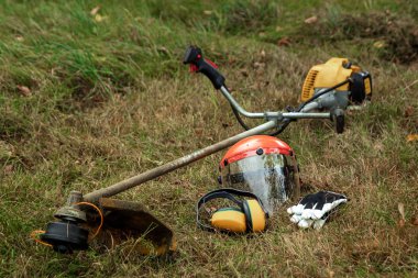 Çim biçmek için aletler ve ekipmanlar, çimenler yerde yatıyor, bir çim biçme makinesi. Çim biçme, yol kenarları, çim biçme.