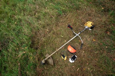 Çim biçmek için aletler ve ekipmanlar, çimenler yerde yatıyor, bir çim biçme makinesi. Çim biçme, yol kenarları, çim biçme.