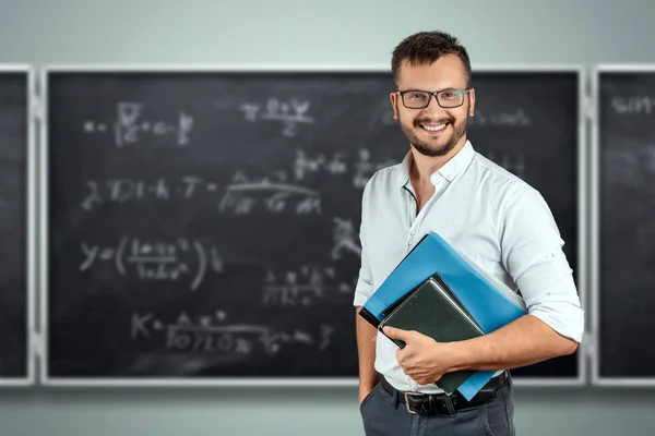 Portrait of a young male teacher on the background of the school blackboard. Teacher's Day Knowledge Day back to school study online learning. — Stock Photo, Image