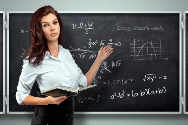 Portrait of a young beautiful teacher on the background of the school blackboard. Teacher's Day Knowledge Day back to school study online learning. — Stock Photo, Image