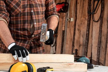 Bir marangoz ağaca çivi çakar, erkek eli çekiçle çekiçtir. Ahşap