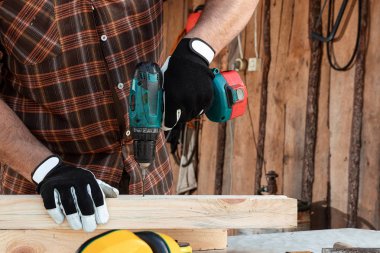 Marangoz bir vidayı elektrikli tornavidayla ağaca çevirir, erkek eli de yakın çekim tornavidayla. Tahtayla çalış.